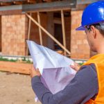 Artisan examinant les plans d’une maison avec une propriétaire avant le début des travaux de rénovation.