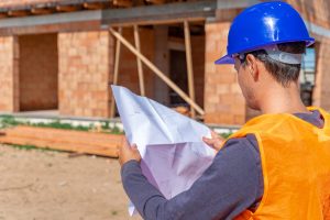 Artisan examinant les plans d’une maison avec une propriétaire avant le début des travaux de rénovation.